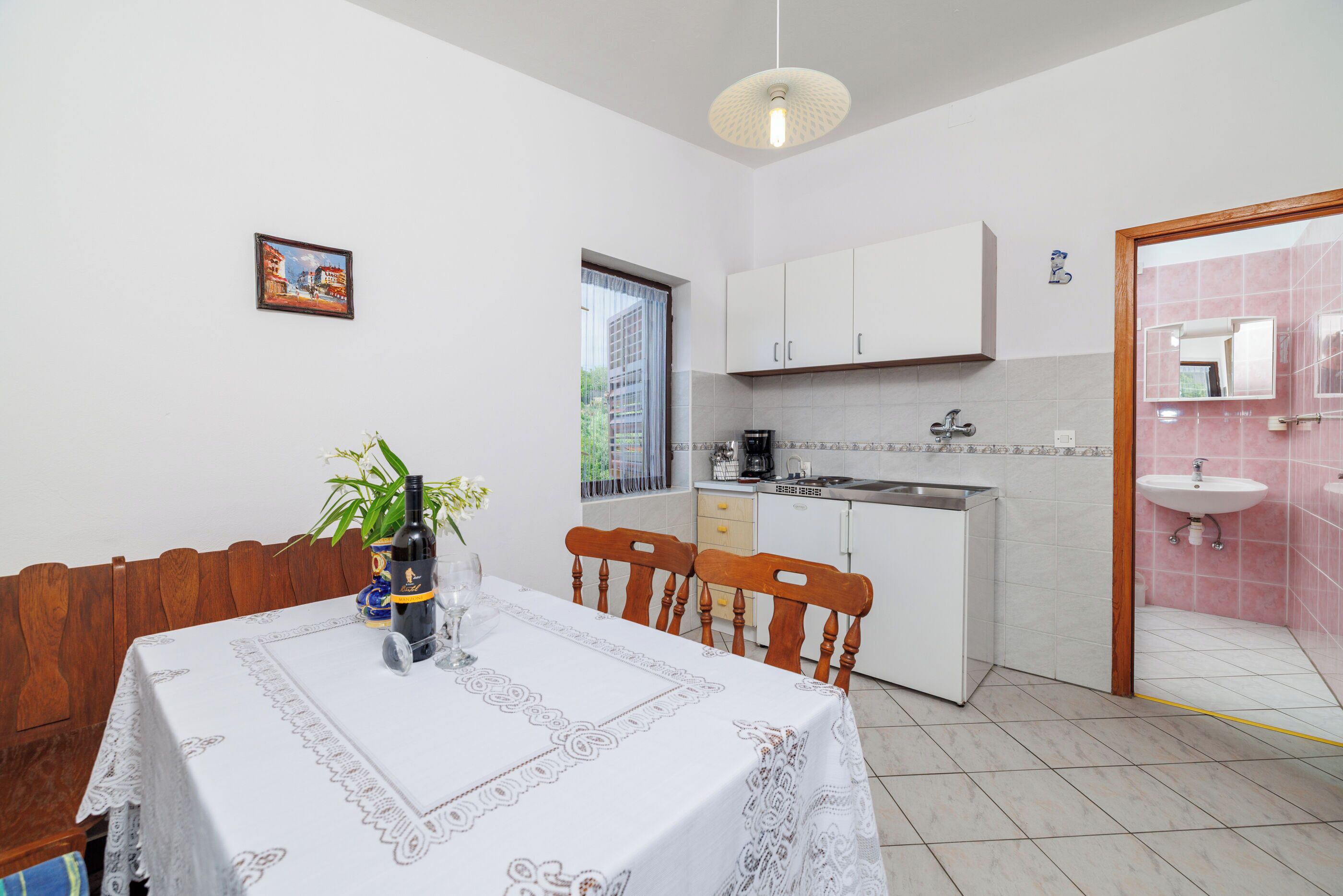 A compact kitchen with white cabinets, a sink, and a dining area with a table set for two.