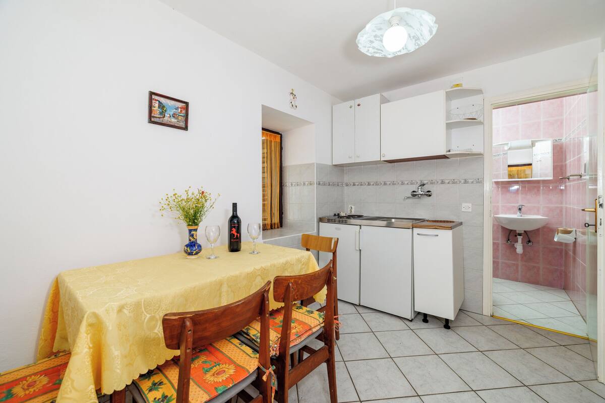 Une cuisine compacte avec des meubles blancs, un évier et un coin repas avec une table mise pour deux personnes.