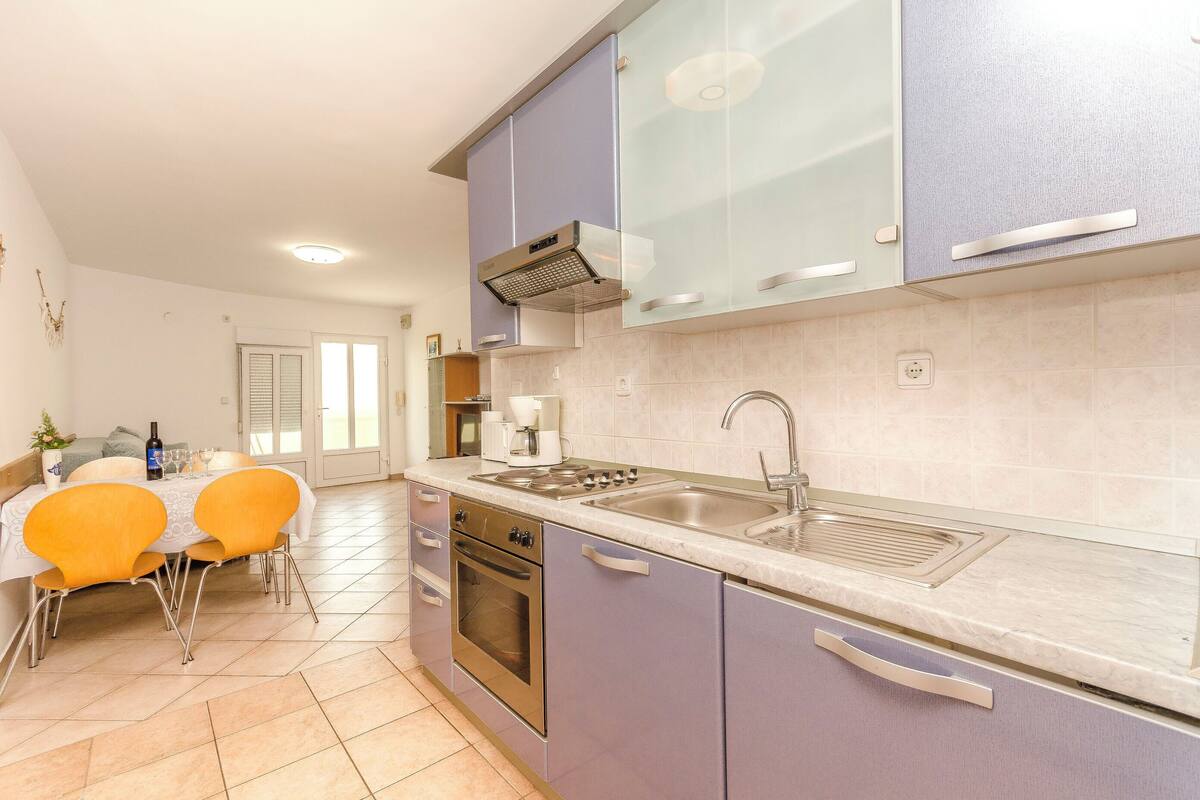 Een moderne keuken met een eethoek, voorzien van een ingebouwde oven, een roestvrijstalen spoelbak en een gasfornuis.