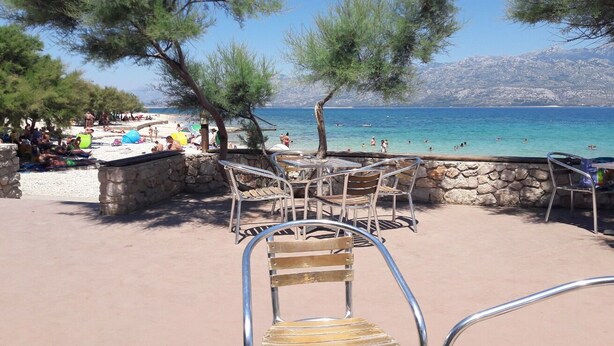 A beachside café with outdoor seating, stone walls, and a view of the sea. - House Dali (Razanac)