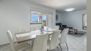 A modern living room with a dining area, featuring a large table with chairs, a sofa, and a coffee table. - House Dali (Razanac)