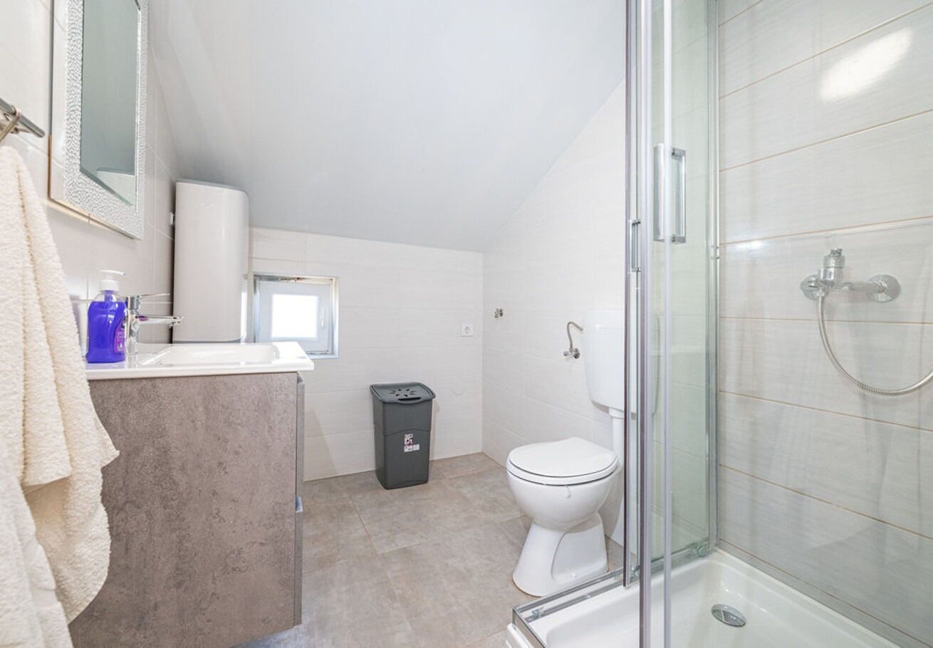 A modern bathroom with a glass shower enclosure, a toilet, and a sink with a towel hanging on the wall.