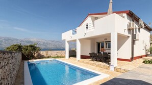 A modern house with a swimming pool, stone walls, and a view of mountains. - House Dali (Razanac)