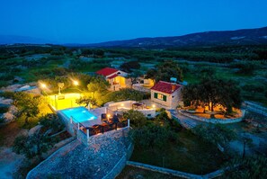 A stone villa with a swimming pool, outdoor seating, and a view of the surrounding landscape. - House Fani (Postira)