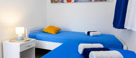 Una habitación de hotel con dos camas, una mesita de noche, una lámpara y un cuadro de lechuzas en la pared.