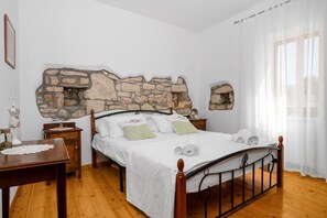 A bedroom with a stone wall, a wooden bed frame, and a wooden floor. - House Bruna (Krsan)