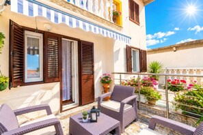 A balcony with wicker furniture, potted plants, and a clear view of the sky. - Apartments Ivi (Rab)
