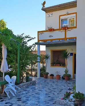 A building with a balcony, potted plants, and outdoor seating. - Apartments Ivi (Rab)
