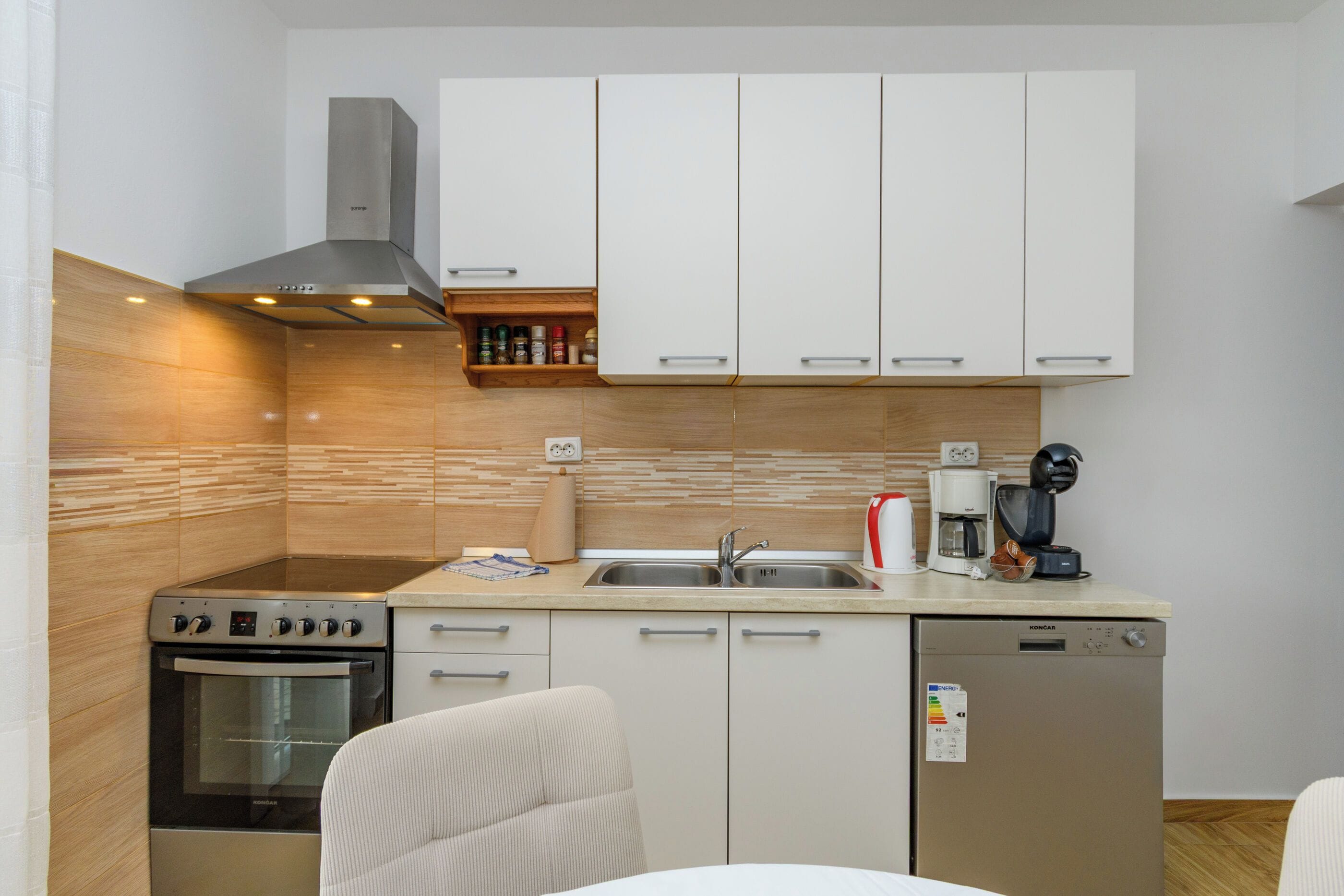 A compact kitchen with a stove, oven, sink, and coffee maker.