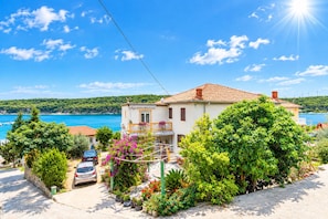 A coastal house with a tiled roof, a balcony, and a view of the sea. - Apartments Ivi (Rab)