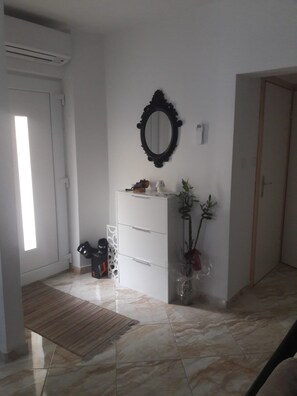 A room with a white dresser, a mirror, a potted plant, and a wooden floor. - Apartments Ivi (Rab)