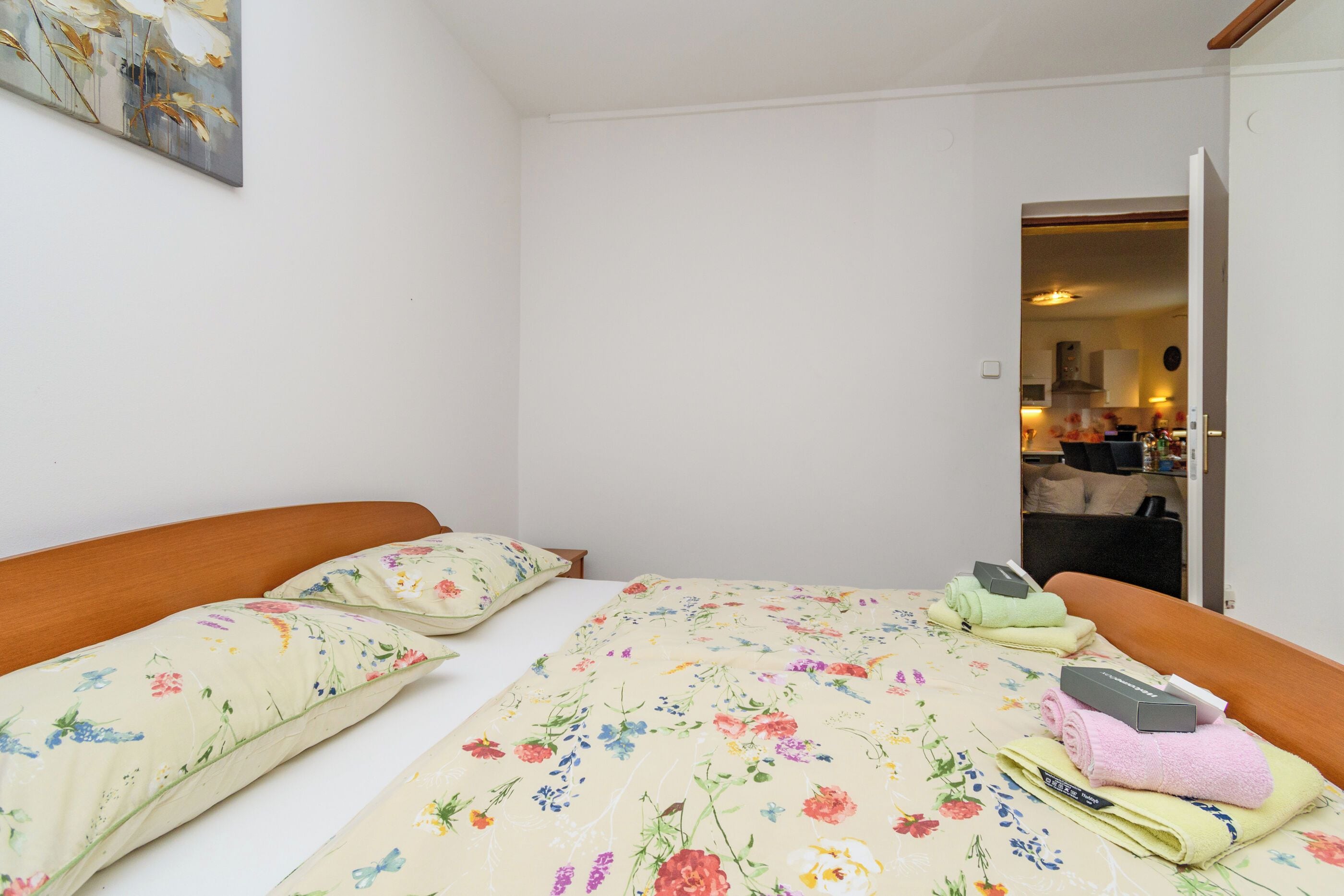 A bedroom with a bed, pillows, and a nightstand with toiletries.
