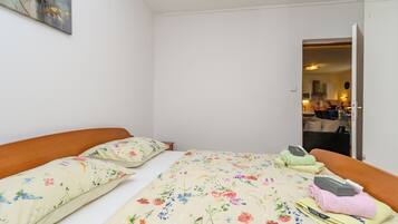 A bedroom with a bed, pillows, and a nightstand with toiletries.