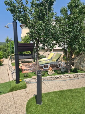 A well-maintained outdoor area with a patio, lounge chairs, and a pergola. - Apartments Ivi (Rab)