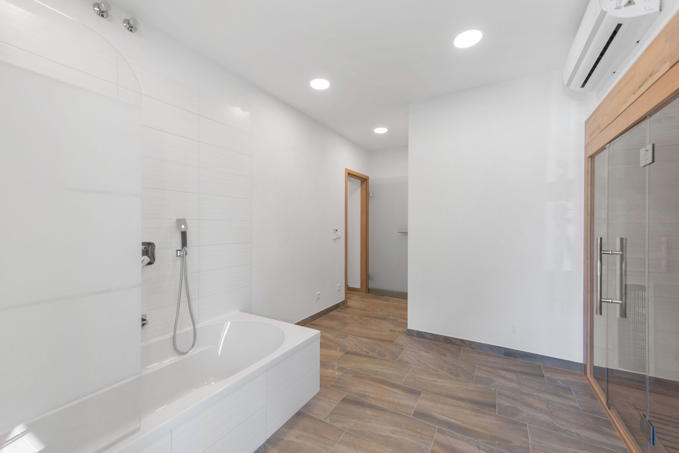 A modern bathroom with a bathtub, shower, and glass shower enclosure.