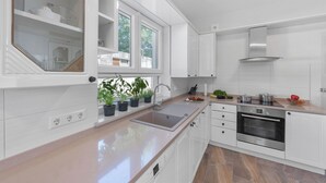 Una cucina moderna con mobili bianchi, un forno in acciaio inossidabile e una finestra con piante.