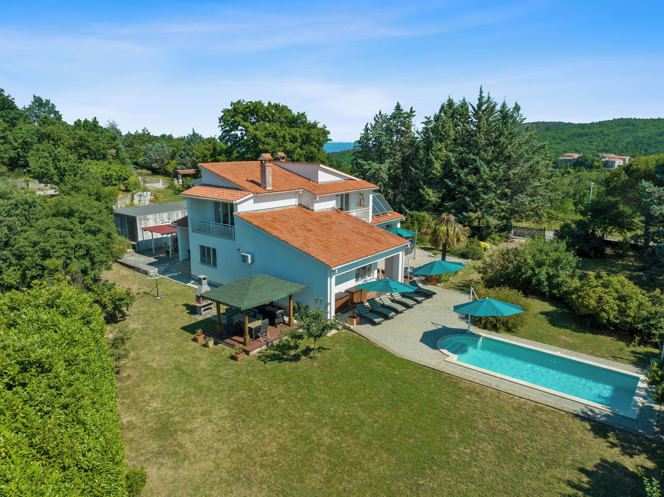 Ein zweistöckiges Haus mit Schwimmbad, umgeben von üppiger Vegetation und Bäumen.
