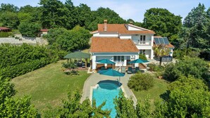 Una casa a due piani con piscina, immersa nel verde.