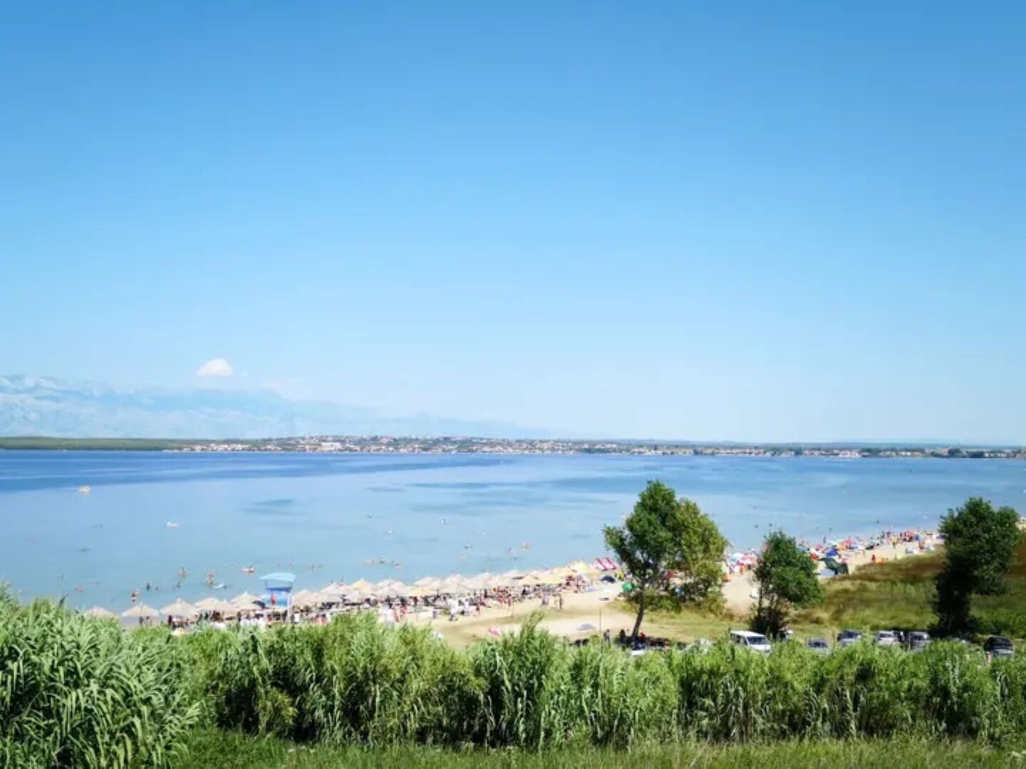 A beach with people, umbrellas, and boats.