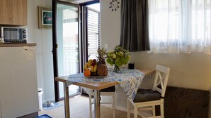 Una cocina pequeña con microondas, refrigerador y comedor con mesa dispuesta para dos.