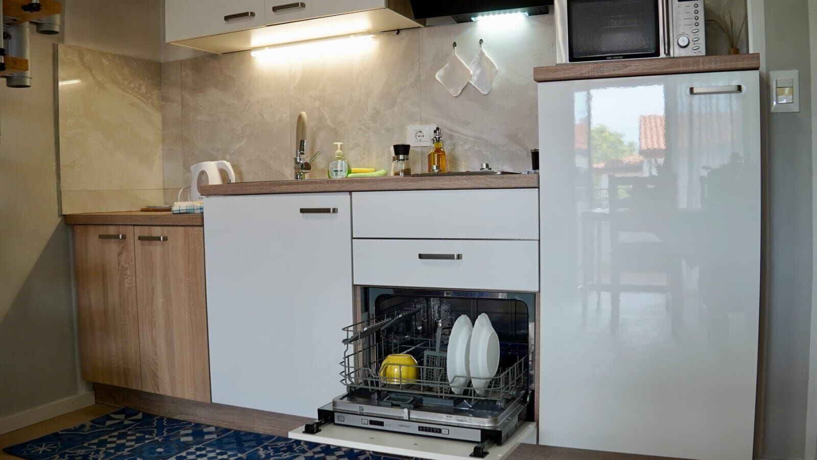 Una cocina compacta equipada con lavavajillas, microondas y refrigerador.