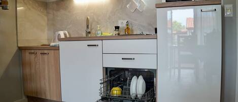 Una cuina compacta amb rentaplats, microones i nevera.