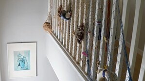 Una escalera con barandilla blanca, una barrera de red y un cuadro en la pared.