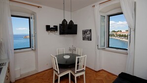 Ein Essbereich mit einem runden Tisch, Stühlen, einer Deckenleuchte und einem an der Wand montierten Fernseher.
