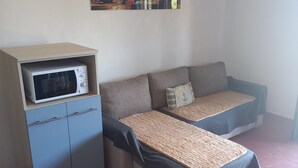 Une chambre équipée d’un canapé-lit, d’un four à micro-ondes et d’un tableau accroché au mur.