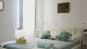 Ein Schlafzimmer mit Bett, Deckenventilator, einem Gemälde und einem Fenster.