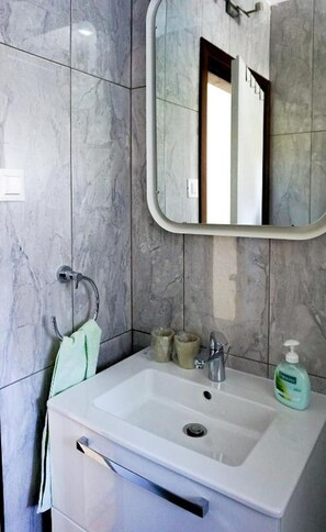 A bathroom with a white sink, a mirror, and a towel rack. - Apartment Vinci 1906 (Vrsar)