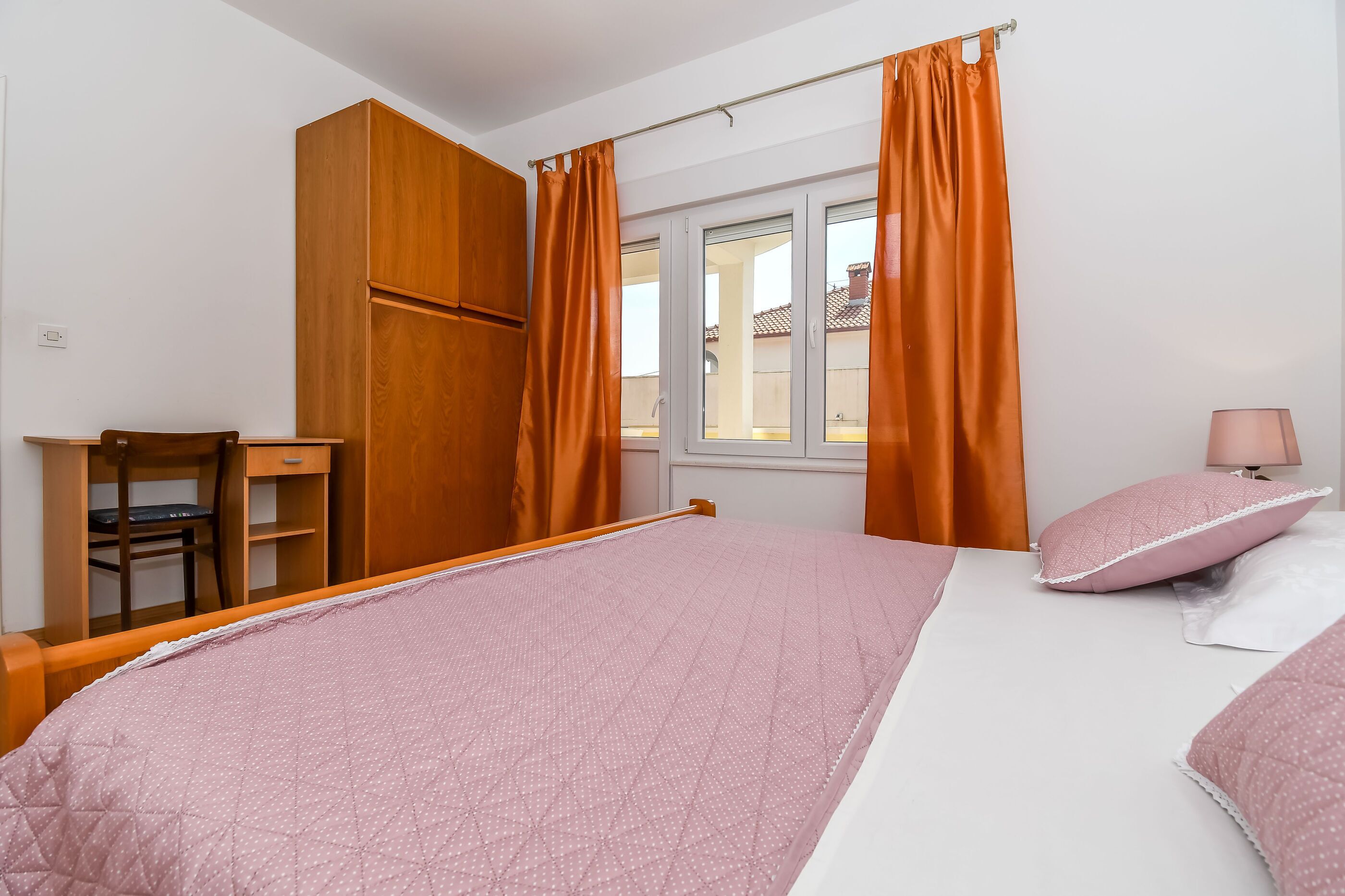 Un dormitorio con una cama, un escritorio y una silla.