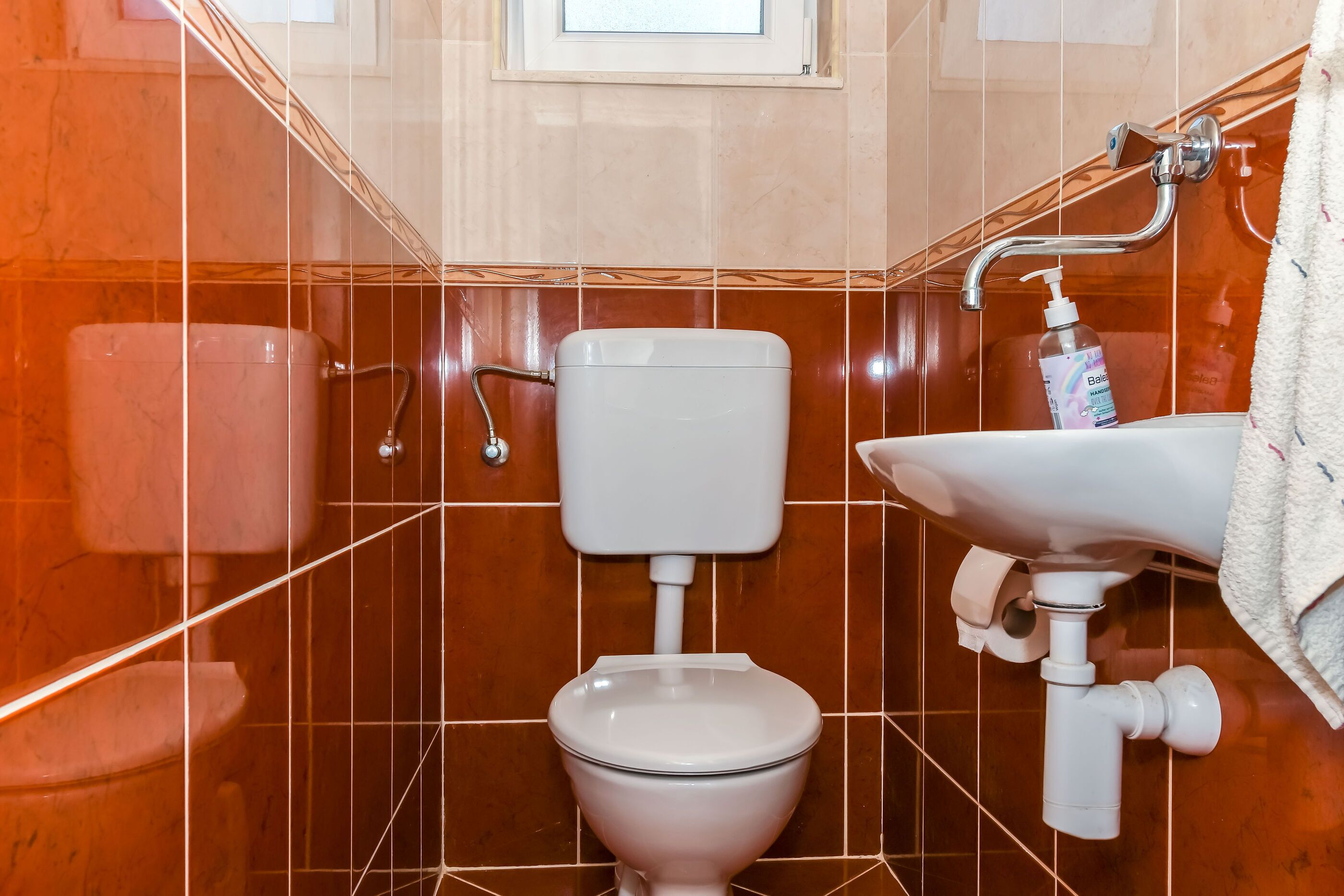 A bathroom with a white toilet, a sink, and a bottle of hand soap.