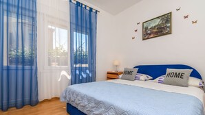 A bedroom with a bed, curtains, a painting, and a pillow with "HOME" on it. - Apartments Tabak (Okrug)