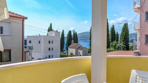 A balcony with yellow walls, white chairs, and a table. - Apartments Tabak (Okrug)