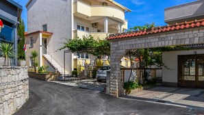 A residential street with a two-story building, a stone archway, and a parked car. - Apartments Tabak (Okrug)