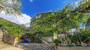 A building with a green facade, a staircase leading to the entrance, and potted plants around the area. - Apartments Sanja (Rab)