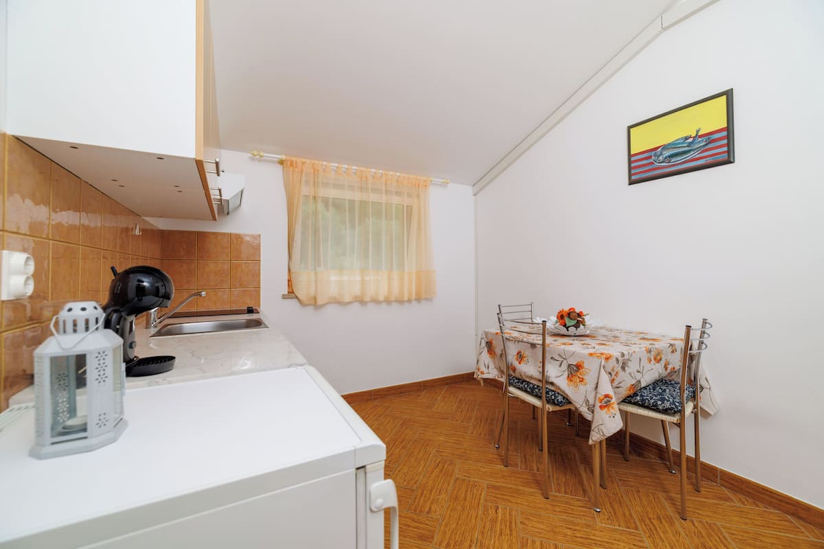 A kitchen with a sink, a kettle, and a table with chairs.