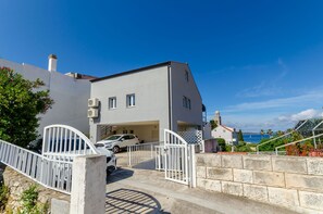 Ein zweistöckiges Haus mit Garage, weißer Fassade und Meerblick.