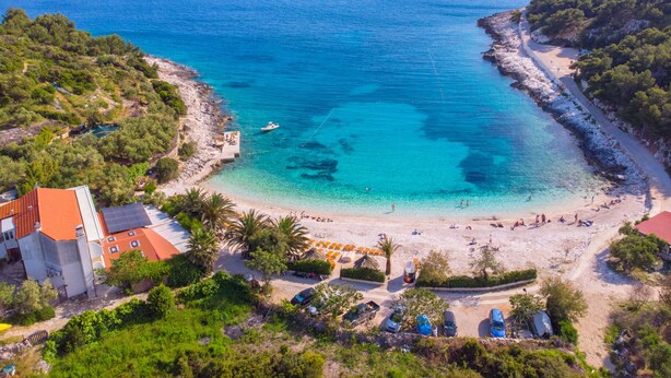 A coastal area with a beach, a small island, and a building with a red roof. - Apartments Marika (Hvar)