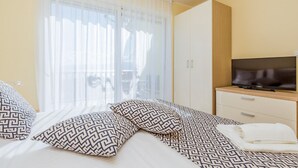 A hotel room with a bed, a TV, a wardrobe, and a balcony with a view. - Apartments Kostrena (Kostrena)