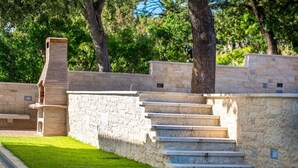 A stone staircase leading up to a wooden structure, surrounded by a well-maintained lawn and trees. - Apartments Kostrena (Kostrena)