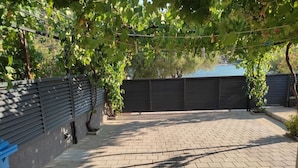 A paved patio area with a brick floor, surrounded by a low wall and a metal fence. - Apartments Neve Beachfront (Sibenik)