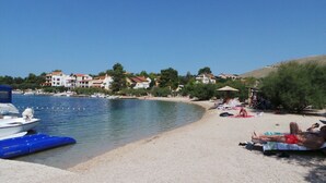 A beach with boats, a sandy shore, and buildings in the background. - Apartments Neve Beachfront (Sibenik)