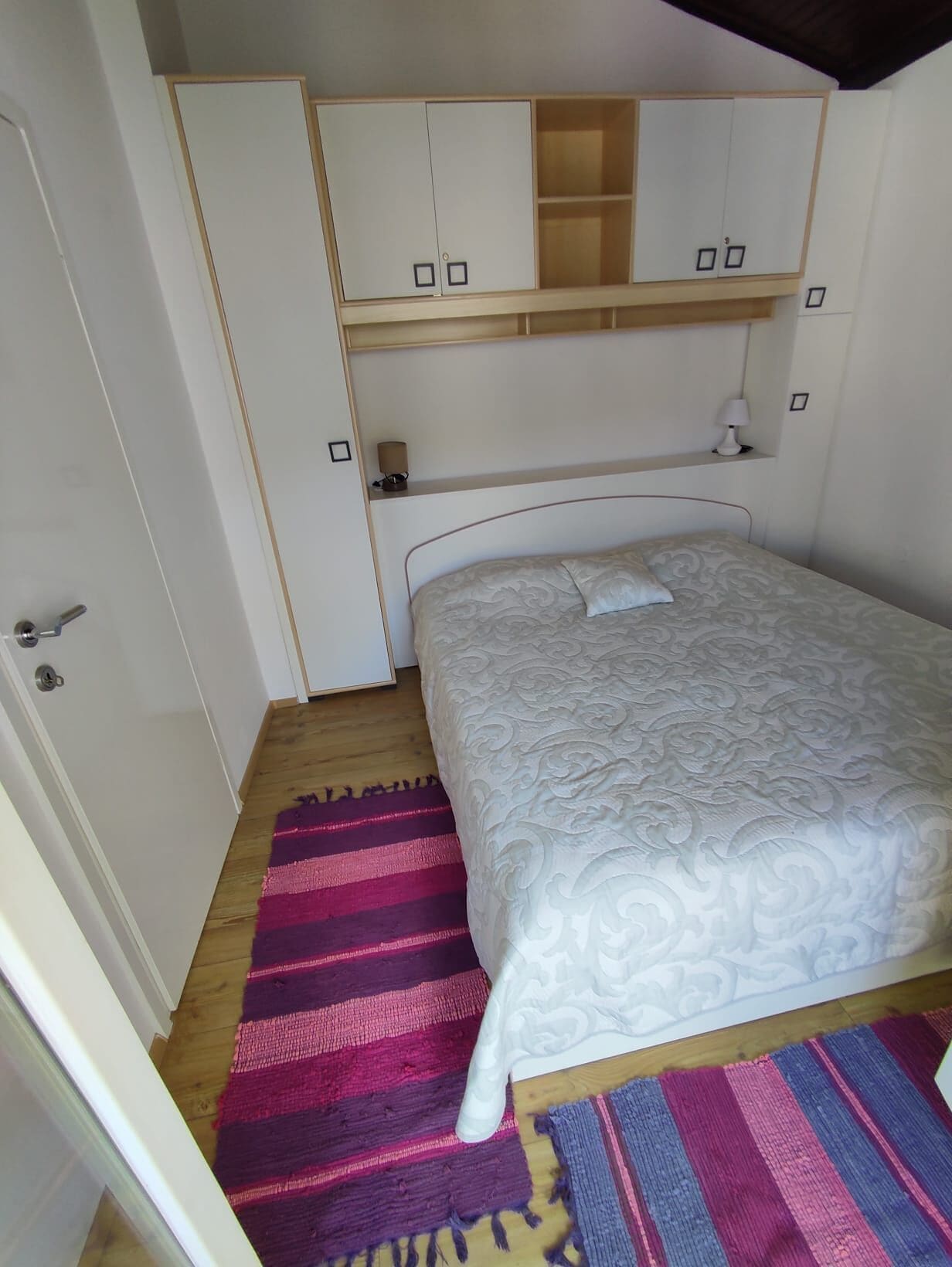Ein Schlafzimmer mit einem Bett, einem Kleiderschrank, einem Nachttisch und einem Teppich.