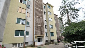 A multi-story residential building with a central entrance, balconies, and potted plants. - Apartment City (Rijeka)