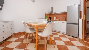 Un angolo cottura funzionale con tavolo e sedie, frigorifero e macchina del caffè.