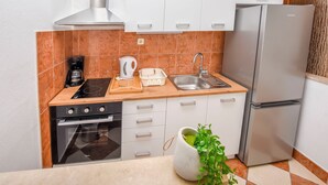 Una cucina moderna con mobili bianchi, un frigorifero in acciaio inossidabile, forno a incasso, macchina del caffè e lavello.
