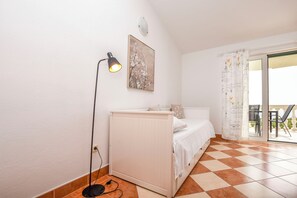 Egy hálószoba, amelyben van egy ágy, egy éjjeliszemélyzet, egy falra szerelt lámpa és egy függönnyel ellátott ablak.