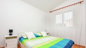 Una camera da letto con un letto, un comodino, una lampada e una finestra con tende.